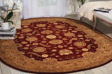 Living room scene with a ruby and gold Nourison 2000 Persian rug, white bench, and floral accents.
