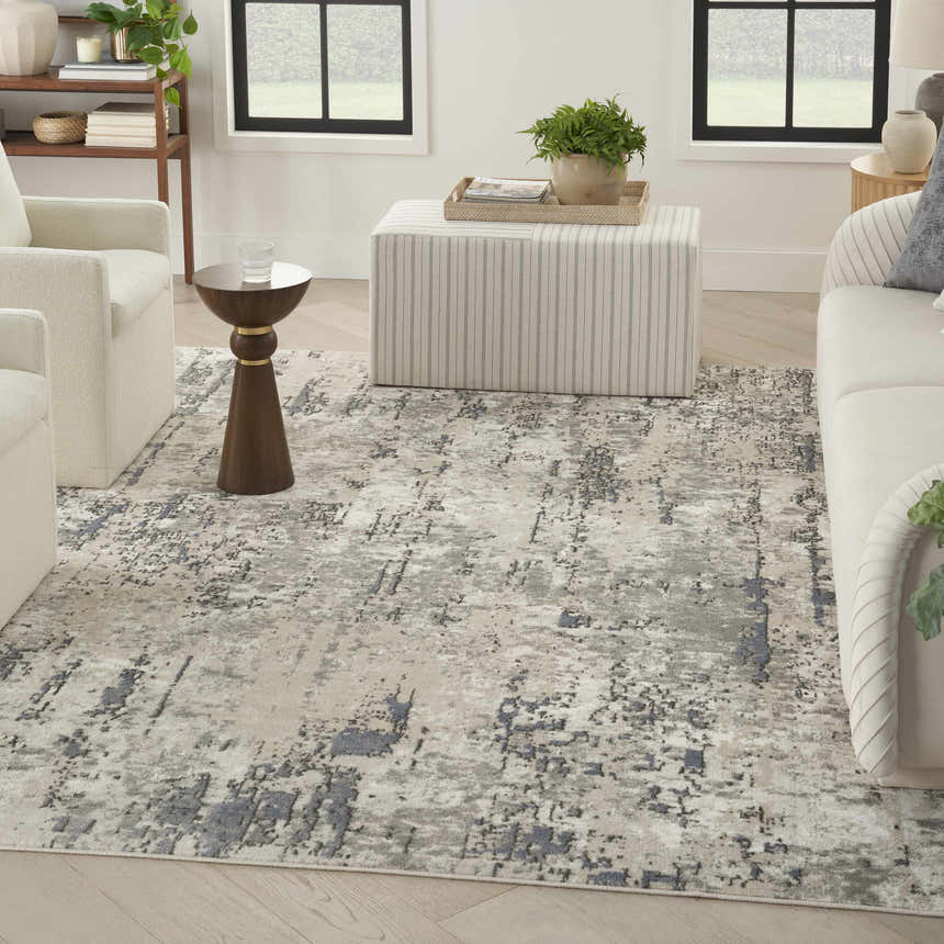 Living room scene with Nourison Quarry Ivory Blue Grey modern rug, white sofa and chairs, and striped ottoman.