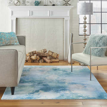 Living room scene with a seafoam Nourison Le Reve rug, gray sofa, fireplace, and modern decor.