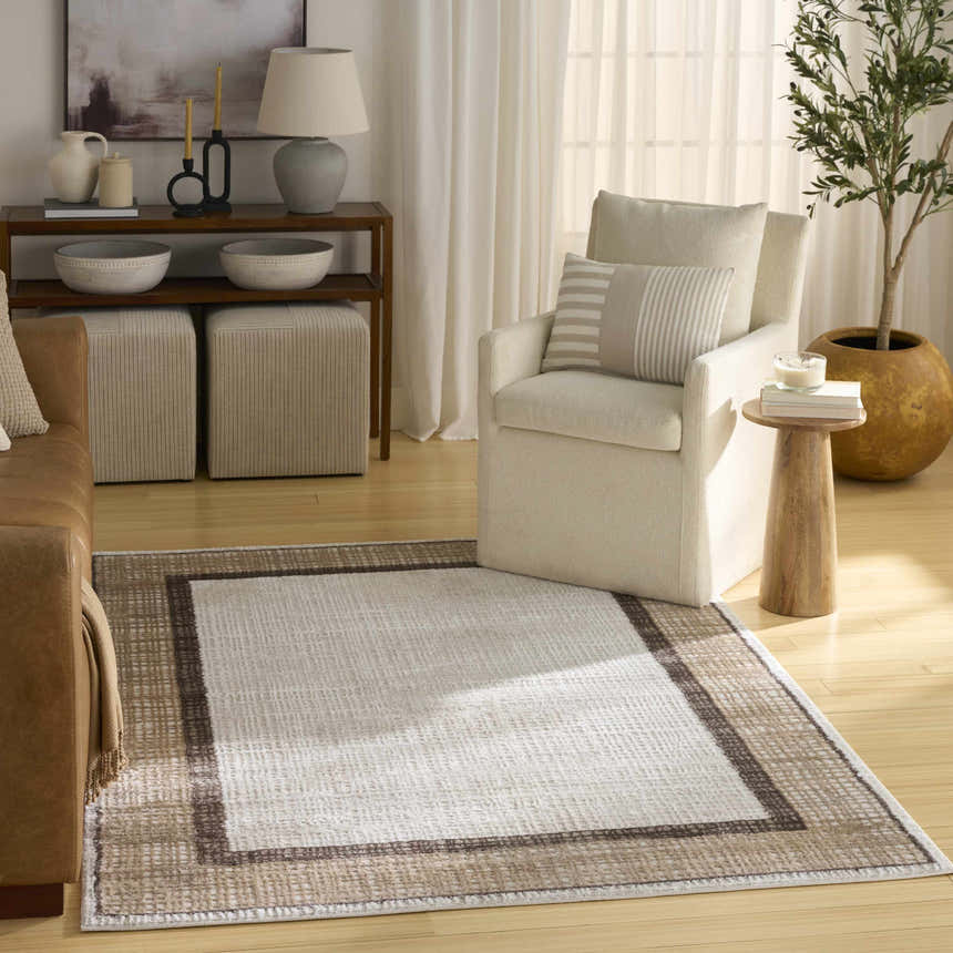 Living room scene with a Nourison Dekor Ivory Brown rug, leather sofa, and neutral armchair.