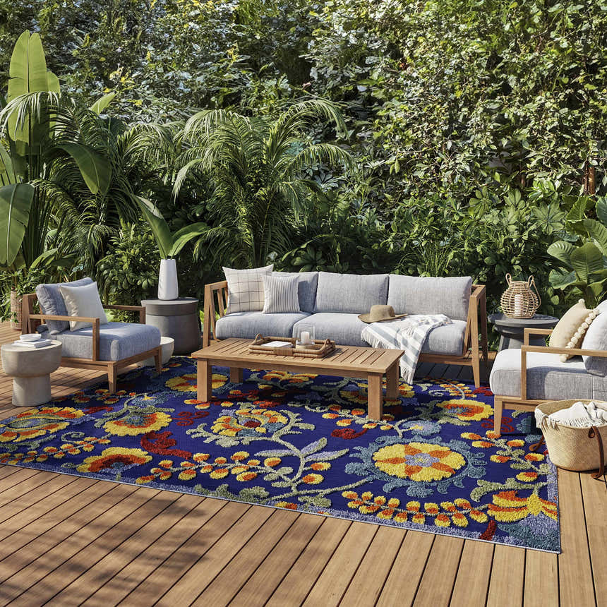 Outdoor patio with gray furniture and Nourison Aloha Navy Multicolor rug with floral pattern on wood deck.
