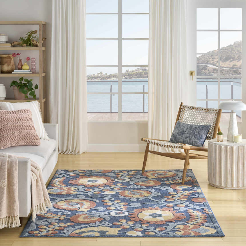 Coastal living room with white sofa, chair, and Nourison Aloha Blue Rose Farmhouse Area Rug with floral pattern.