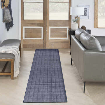 Entryway with a Nourison Navy Blue Modern Washable Area Rug runner, gray bench, and leather sofa.