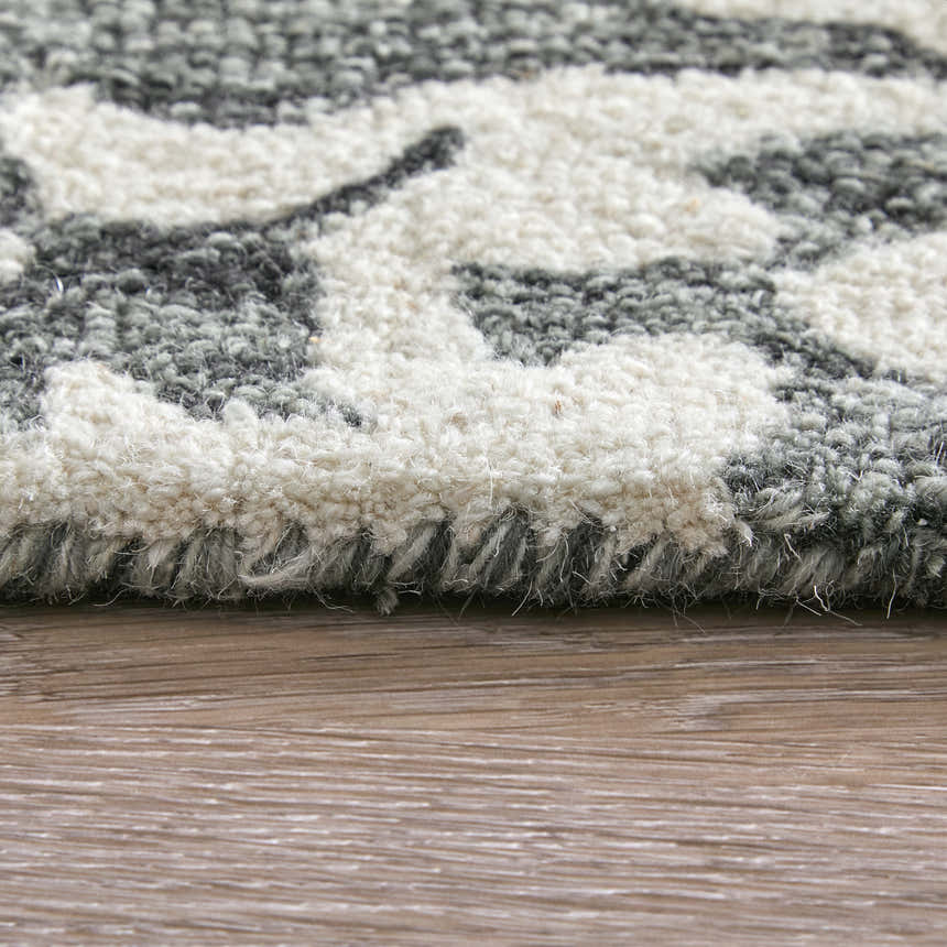 Close-up of the Feizy Belfort rug showing its hand-tufted wool texture and gray, ivory, and black floral pattern. Pile