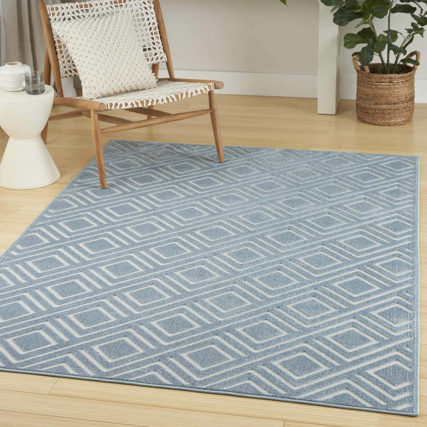 Modern living room scene with a light blue Nourison Care Free area rug featuring a geometric diamond pattern.