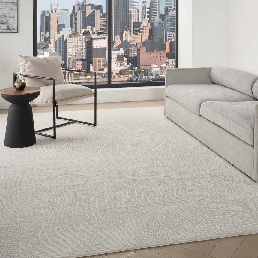 Modern living room with a DKNY Central Park West ivory rug, gray sofa, chair, and city view.