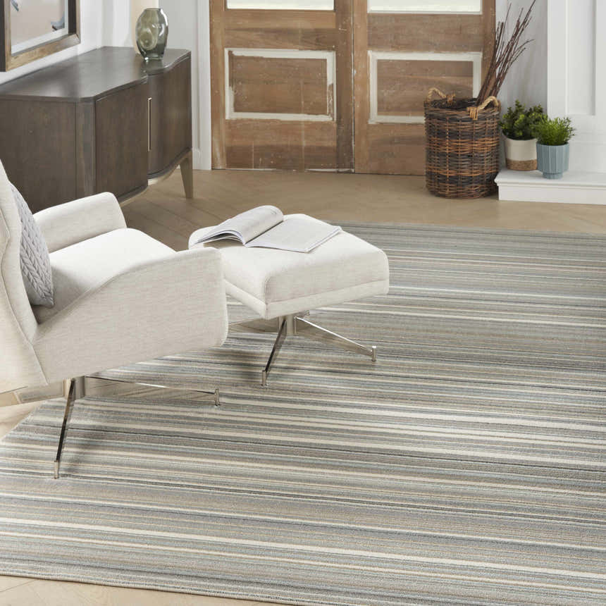 Living room scene with Nourison Marmara Grey rug, white chair and ottoman, and neutral decor.