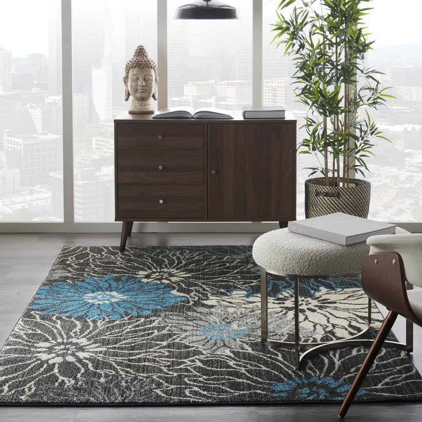 Modern living room with Nourison Passion Charcoal Blue rug, wood cabinet, and city view.