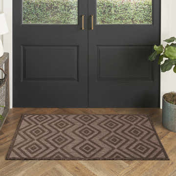 Entryway with dark brown doors and a Nourison Versatile Brown Modern Area Rug with a diamond pattern on wood floors.