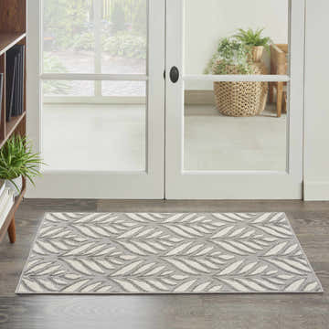 Entryway with Nourison Aloha Grey Tropical Area Rug featuring a leaf pattern on dark wood floors.