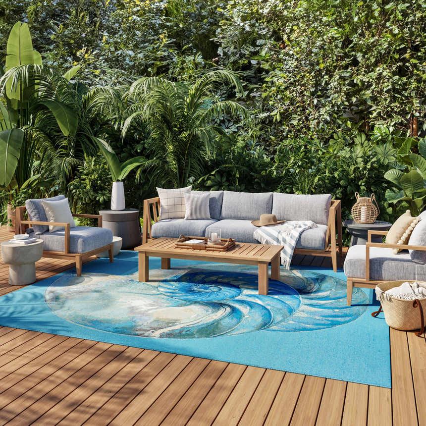 Coastal patio with gray furniture and Nourison Color Splash Blue Ivory Area Rug featuring a nautilus design.