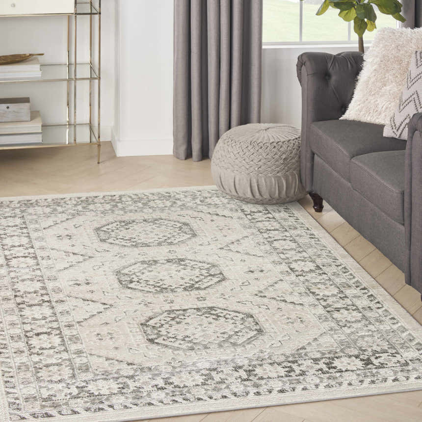 Living room scene with grey sofa and Nourison Serenity Home Ivory Grey Vintage rug on wood floor.