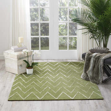 Sunlit room with a Nourison Vita Kiwi rug, light green with a white chevron pattern, paired with a plant and bench.
