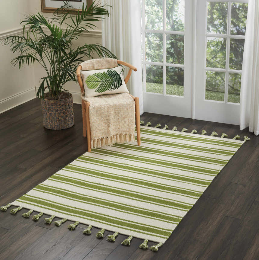 Sunlit room with Nourison Rio Vista Ivory/Green rug, wood chair with throw, and potted palm. Fresh, natural aesthetic.