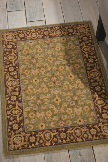 Close-up of Nourison Persian Empire Green Persian rug on a whitewashed wood floor. Features floral designs and a brown border.