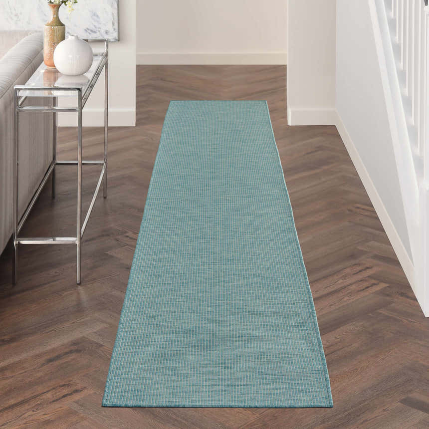 Hallway with Nourison Positano Aqua Modern Area Rug runner, wood floors, console table, and neutral decor.