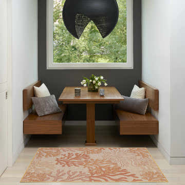 Breakfast nook with Nourison Garden Oasis Coral rug, wood benches, gray wall, and modern light fixture.