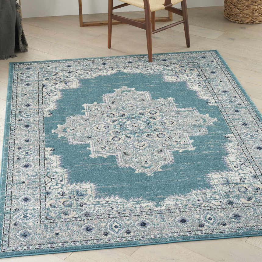 Light wood floor with Nourison Passion Turquoise Grey rug, chair legs visible.