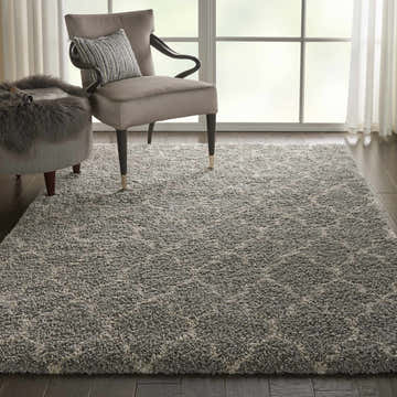 Living room scene with ash gray Nourison Amore shag rug, armchair, ottoman, dark wood floors, and soft natural light.