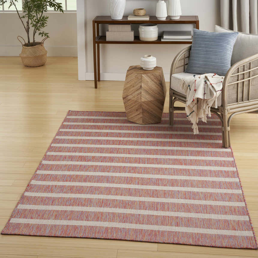 Living room scene with a Nourison Positano Rainbow Ivory rug, light wood floors, and a rattan chair with blue pillow.
