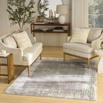 Living room scene with a Nourison Pacific Shag Grey rug, cream sofa, chair, wood accents, and natural light.