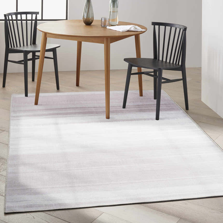 Dining room with a Calvin Klein Launder Ivory rug under a wood table and black chairs.