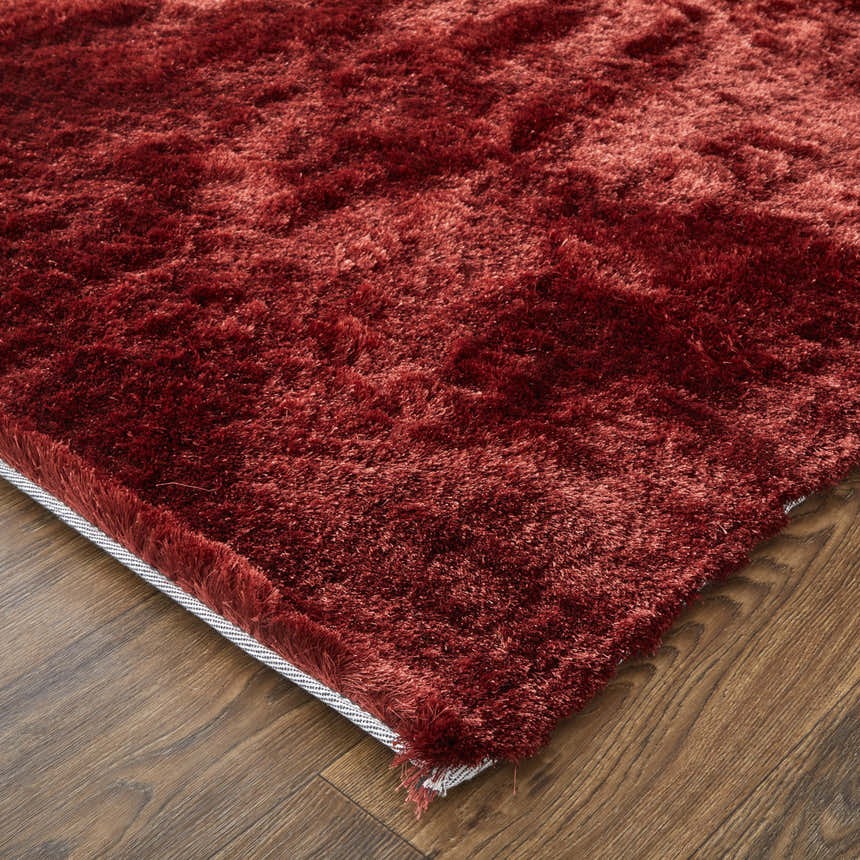 Close-up of the plush texture and rich red-orange color of the Feizy Indochine Modern Solid Area Rug. Corner