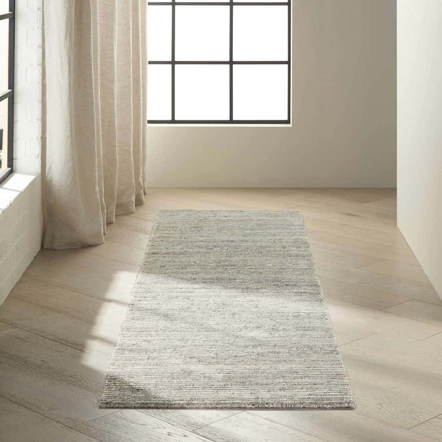 Bright room scene with a grey Calvin Klein Kathmandu runner rug on light wood floors.