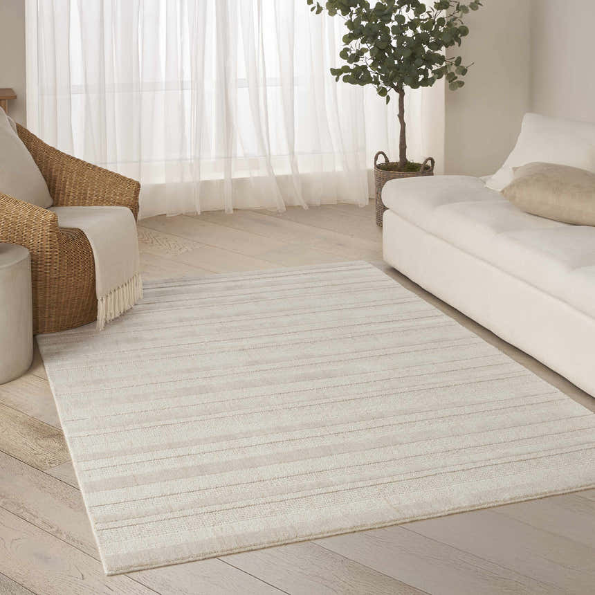Living room scene with DKNY Pure Multi Weave Ivory rug, white sofa, and wicker chair for a calm, contemporary feel.
