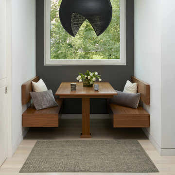 Breakfast nook with wood benches, table, and olive Nourison Tulum Olive Outdoor Area Rug.