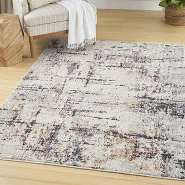 Living room scene with a Nourison Motion Ivory Multicolor rug, neutral chair, and light wood floors.