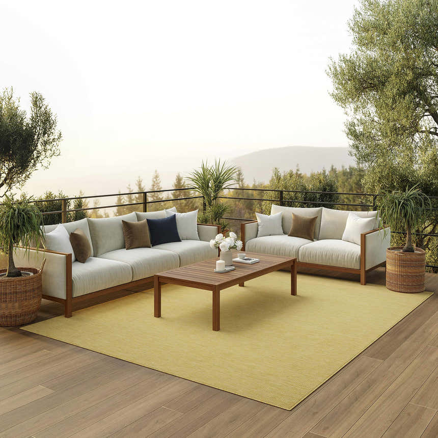 Outdoor living space with Nourison Positano Yellow rug, sofas, wood table, and scenic mountain view.
