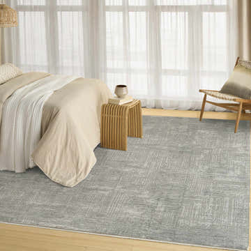 Bedroom scene with DKNY DK014 Madison Slate rug, taupe bedding, wood side table, and sheer curtains.