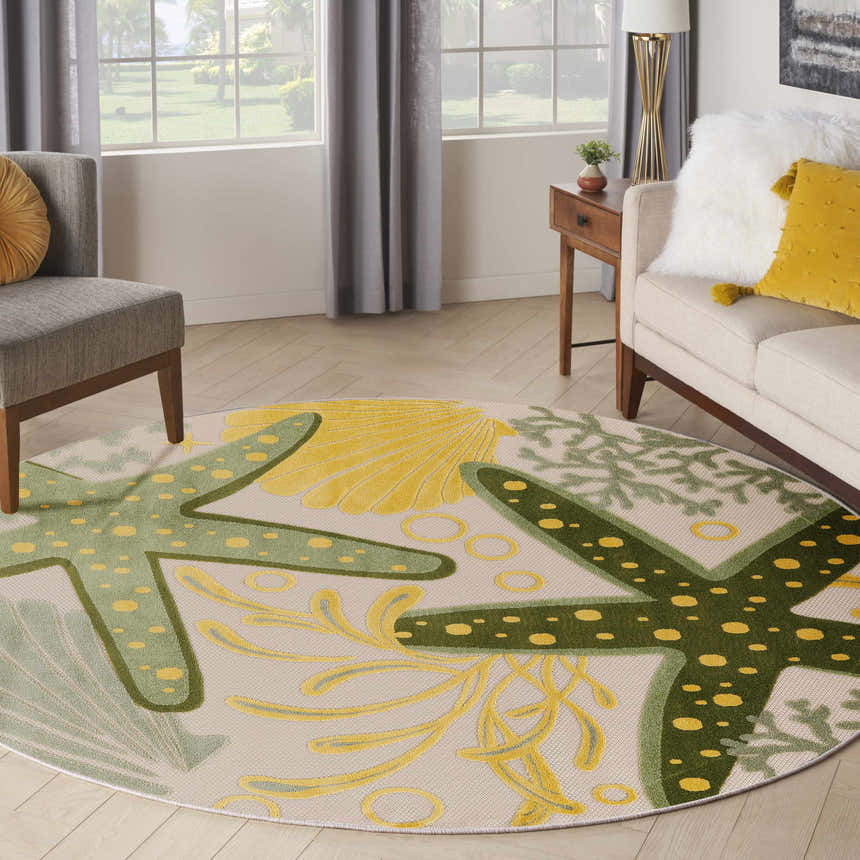 Living room scene with round Nourison Aloha Green Yellow Outdoor Area Rug featuring starfish and coral patterns.