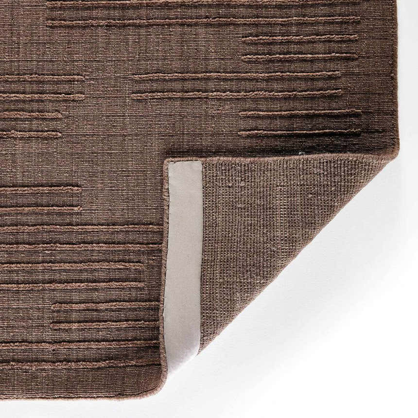 Close up of the taupe Four Hands Geist Rug showing its striped pattern and hand-loomed texture. Fold