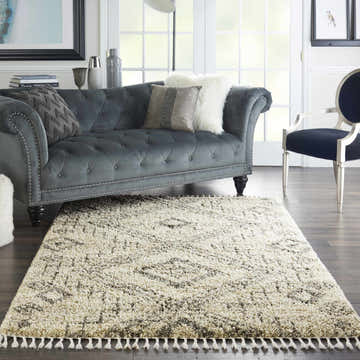 Living room scene with a grey sofa and the Nourison Oslo Shag Ivory/Grey rug with tassels on dark wood floors.