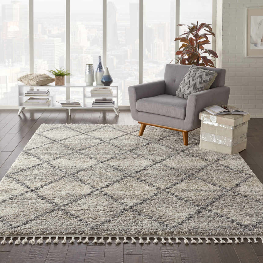 Living room scene with a grey chair and the Nourison Oslo Shag Ivory/Grey rug with a diamond pattern.