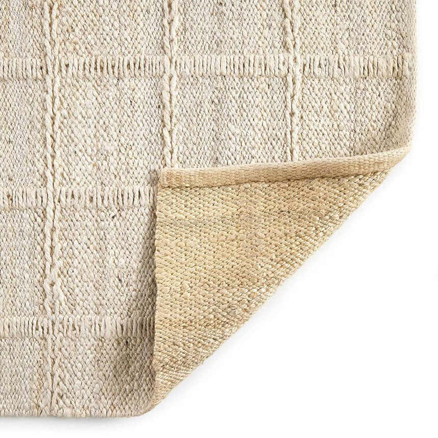 Close-up of the Four Hands Grid Jute Rug - Bleached Grid Jute. Hand-woven natural fiber rug with a subtle grid pattern. Fold