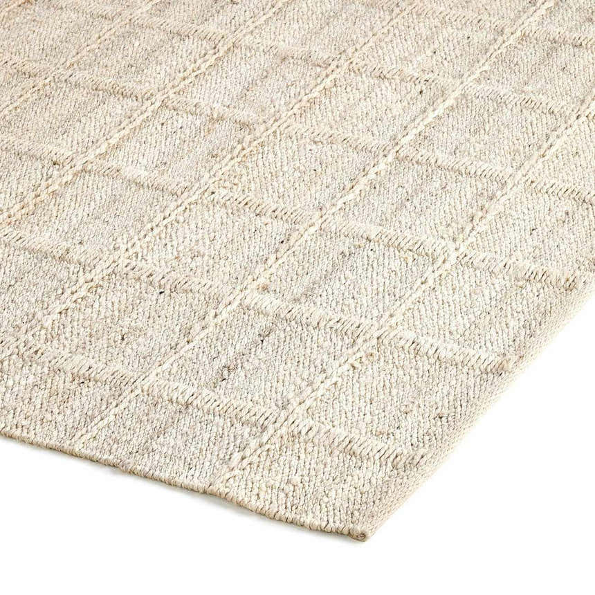 Close-up of the hand woven Four Hands Grid Jute Rug, bleached jute color, with a subtle grid pattern. Corner