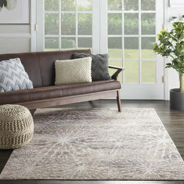 Living room scene with brown sofa, and Nourison Silky Textures Ivory Beige Modern Indoor Area Rug on dark wood floor.
