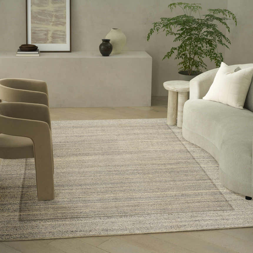 Living room scene with beige chairs and sofa featuring the Calvin Klein CK082 Ridge Grey Ivory rug.