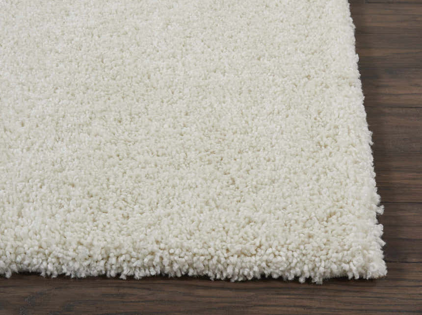 Close-up of the ivory Nourison Malibu Shag rug, showing its plush texture and soft color on a dark wood floor.