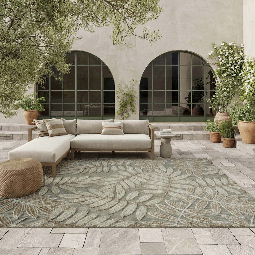 Serene patio with a neutral sectional and Nourison Aloha Natural Tropical Area Rug featuring a large leaf pattern.