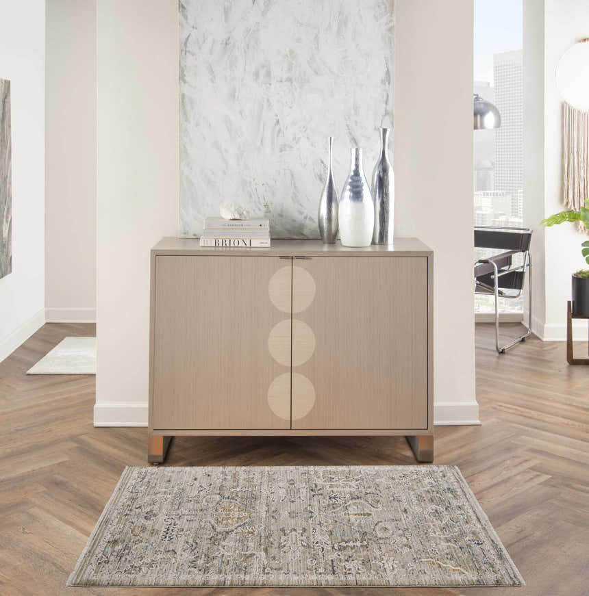 Living room scene with a Nourison Lynx Ivory Taupe vintage rug, wood floors, and modern cabinet with vases.