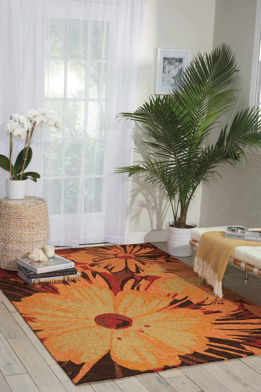 Living room scene with a Nourison South Beach Multicolor Area Rug featuring a large floral design in orange, red, and brown tones.