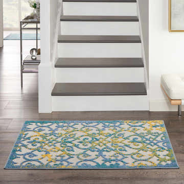 Entryway with Nourison Aloha Ivory Blue Outdoor Area Rug, wood floors, white stairs, and modern decor.