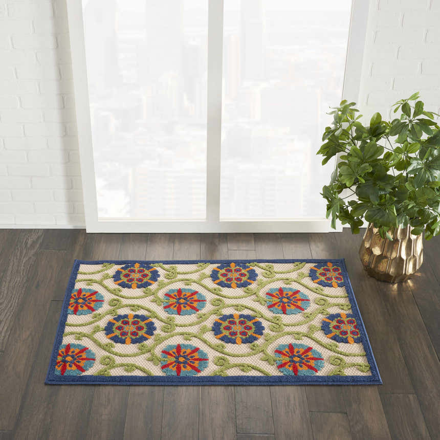 Room scene with Nourison Aloha Blue Multicolor rug on dark wood floor, near window and plant.