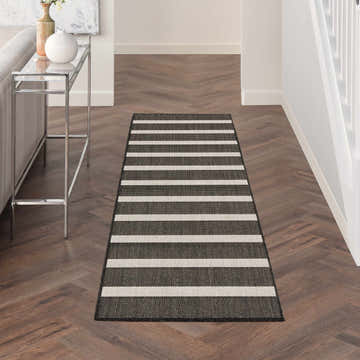 Hallway scene with a Nourison Positano Black Ivory runner rug on dark wood floors. Modern, striped design.
