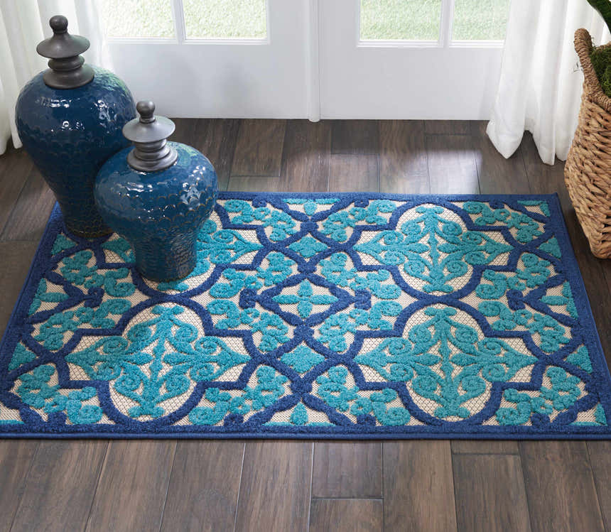 Entryway with Nourison Aloha Navy Bohemian Area Rug, dark wood floor, blue vases, and white door.