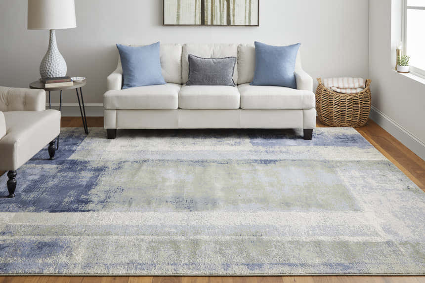 Living room scene with a Feizy Clio blue, green, and ivory abstract rug, white sofa, and wood floors. Roomscene-Rectangle
